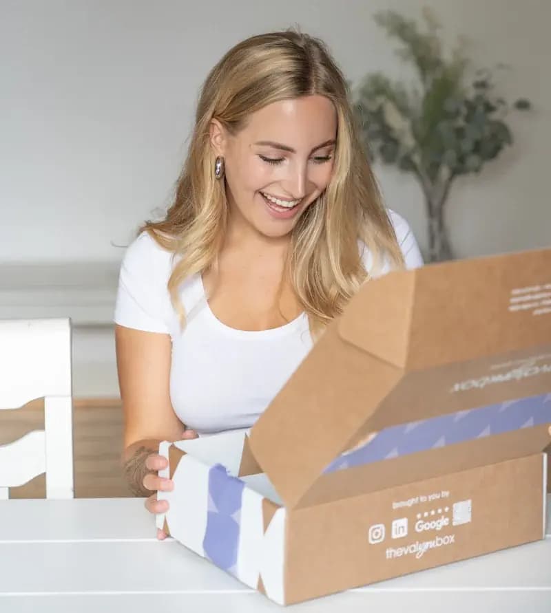 Eine Mitarbeiterin öffnet lächelnd ihre Geschenkbox von thevalyoubox